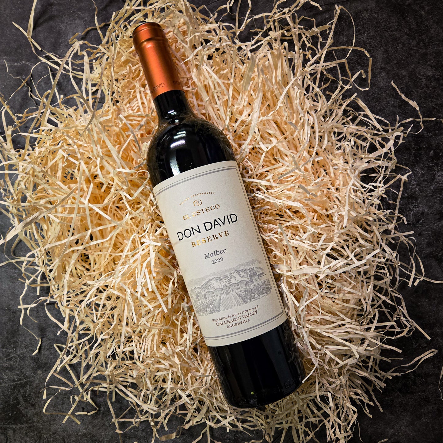 Bottle of Don David Reserve wine on a bed of straw with a dark background